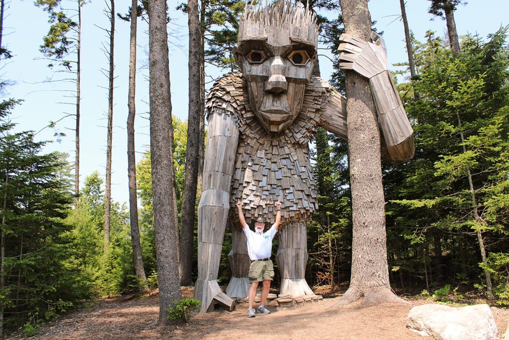 Tourguide with large troll at Coastal Maine Botanical Gardens